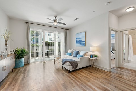 A bedroom with a bed, a plant, and a painting on the wall.