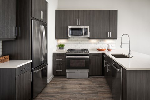 A modern kitchen with dark wood cabinets and stainless steel appliances.
