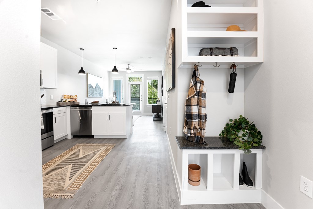 an open kitchen and living room with white cabinets and a counter with a plant