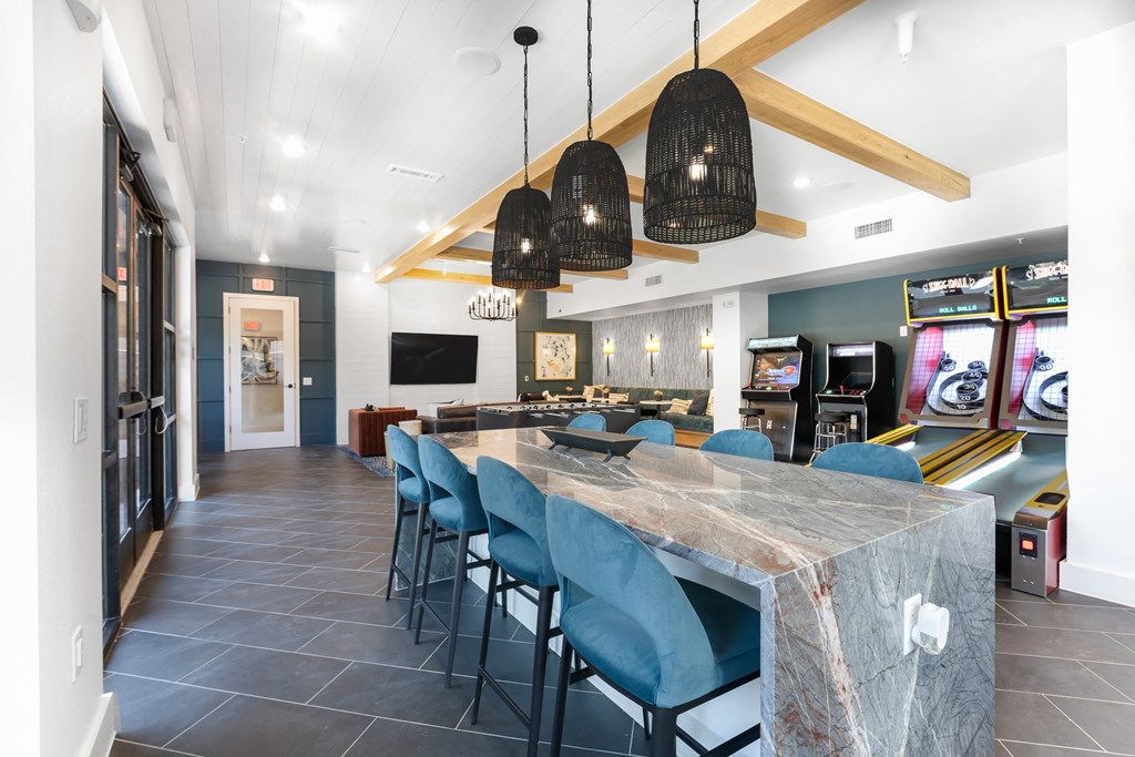 a long dining table with blue chairs in a room with a kitchen and a television