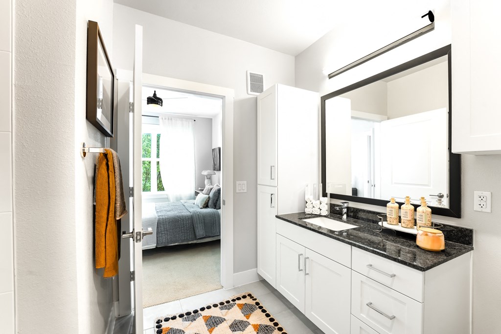 a bathroom with a sink and a mirror and a bedroom