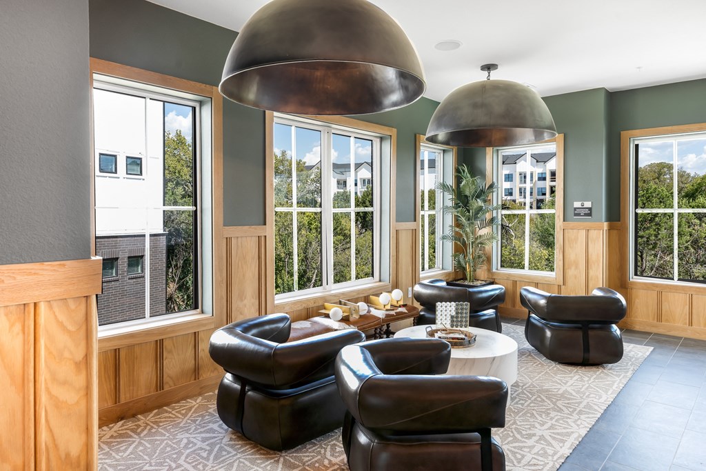 a living room with chairs and a table and large windows