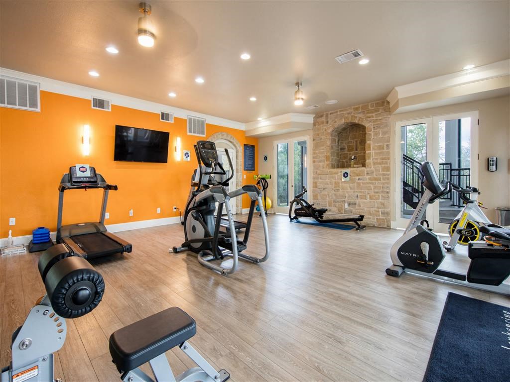 a gym with exercise equipment and a tv on the wall