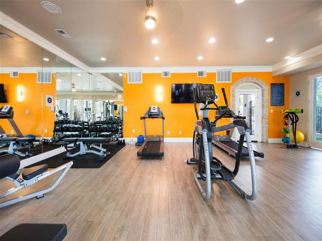 a gym with cardio equipment and a tv on the wall
