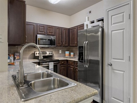 A kitchen with a stainless steel refrigerator and a sink.