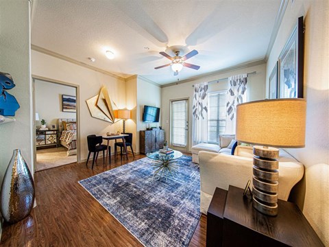 A living room with a blue rug and a ceiling fan.