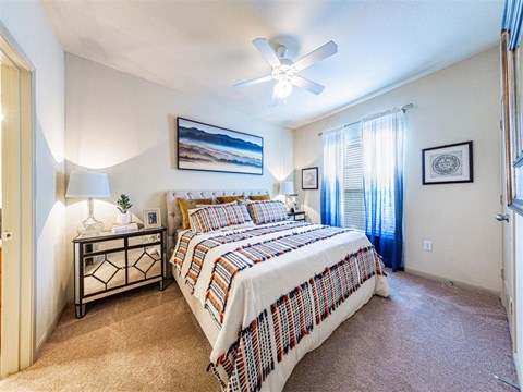 A bedroom with a bed, nightstand, and a ceiling fan.