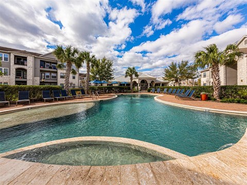 A large outdoor swimming pool surrounded by palm trees and lounge chairs.