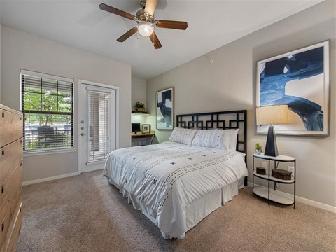 A bedroom with a large bed and a ceiling fan.