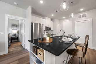 a kitchen with white cabinets and a black counter top