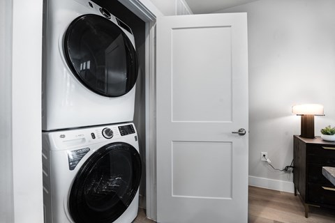 a front loading washer and dryer in a small room with a white door