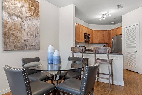 a dining room with a glass table and chairs and a kitchen