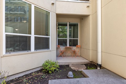 a porch with chairs and a table in front of a building