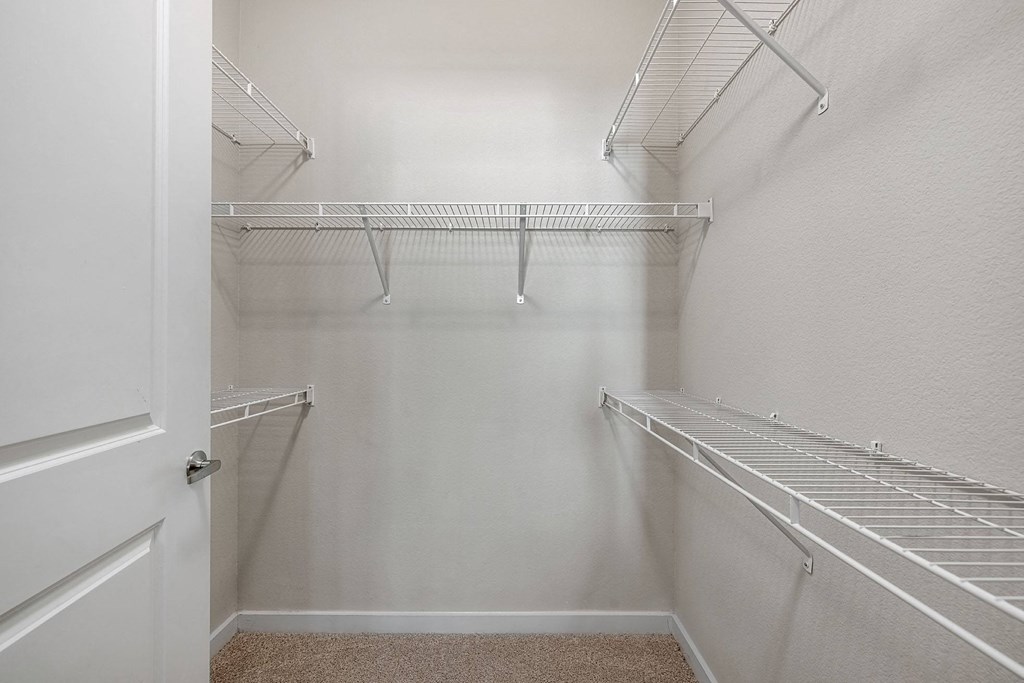 a spacious closet with shelves and a door to a walk in closet
