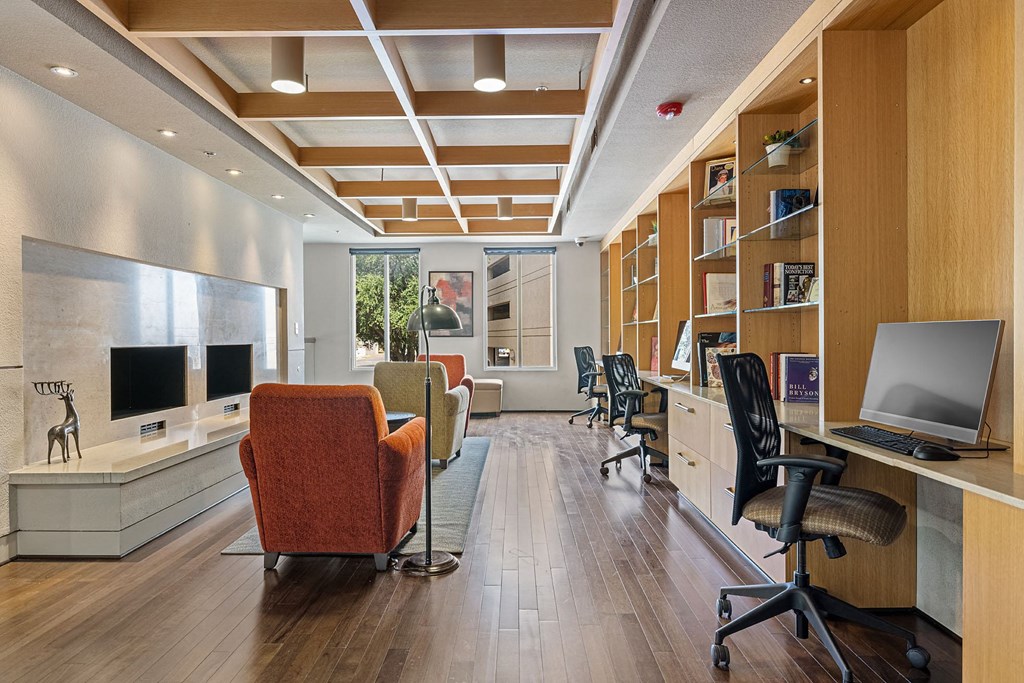 a library with a desk and chairs and a television