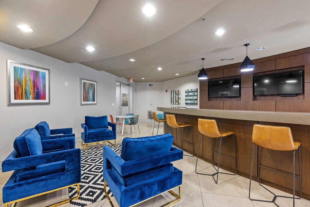 a lobby with blue chairs and a bar with a television
