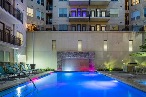 an apartment pool with a blue lighted waterfall in front of an apartment building