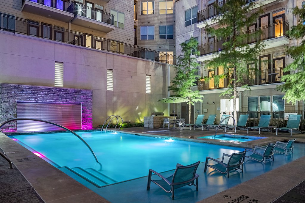 a swimming pool with chairs in front of an apartment building