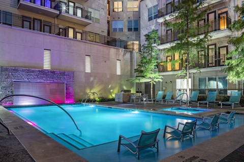 a swimming pool with chairs in front of an apartment building
