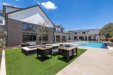 a yard with tables and chairs and a pool in front of a building