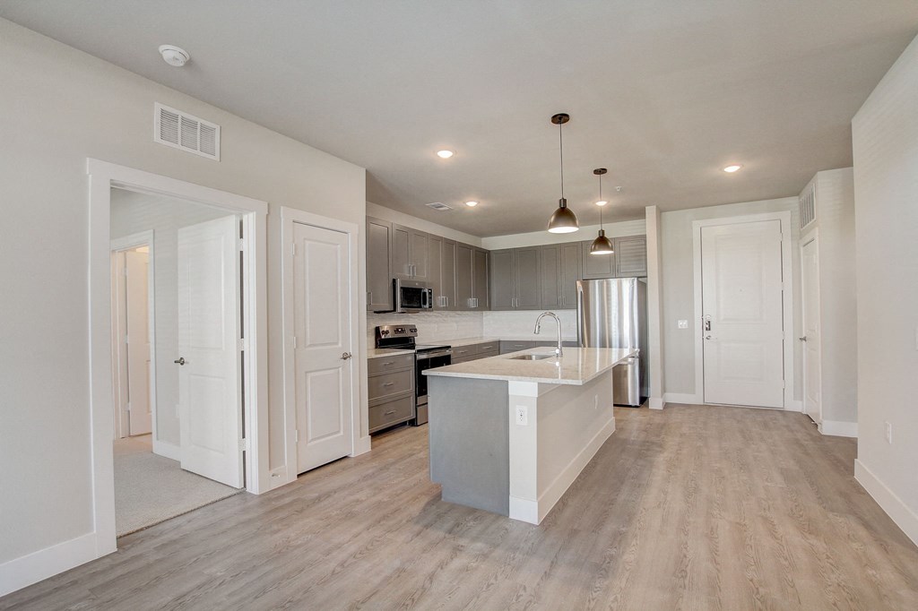 an open kitchen and living room with white cabinets and a white counter top