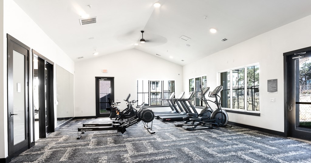 a gym with treadmills and other exercise equipment in a large room with windows