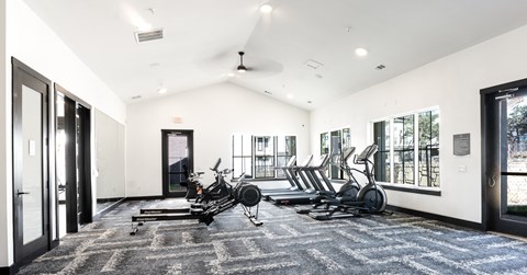 a gym with treadmills and other exercise equipment in a large room with windows