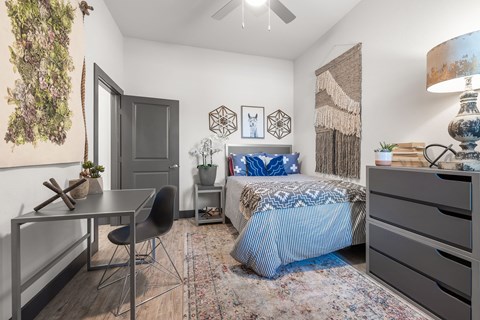 a bedroom with a bed and a desk and a window