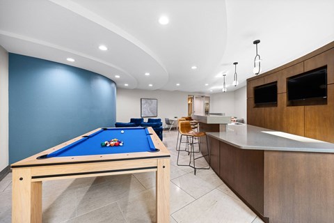 A pool table in a room with a bar counter.