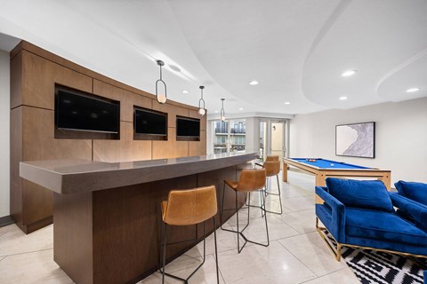 A modern living room with a bar area and a pool table.