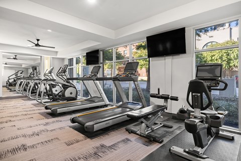 A gym with treadmills, elliptical machines, and a television.