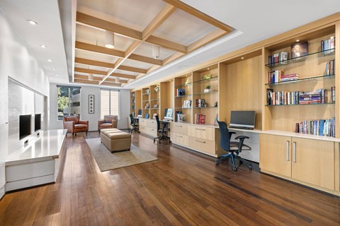 A room with a long wooden floor and a long bookshelf with books on it.