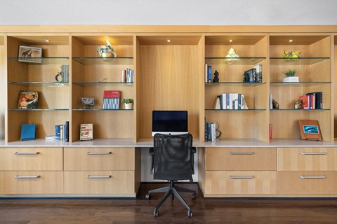A room with a desk, chair, and shelves filled with books and decorative items.