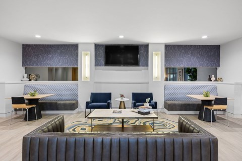 A modern living room with a black leather couch and a television mounted on the wall.