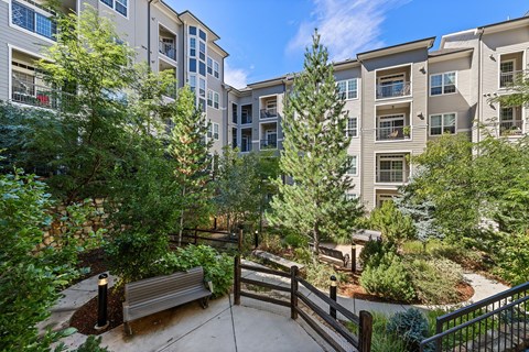 A view of a courtyard with a bench and a fence.