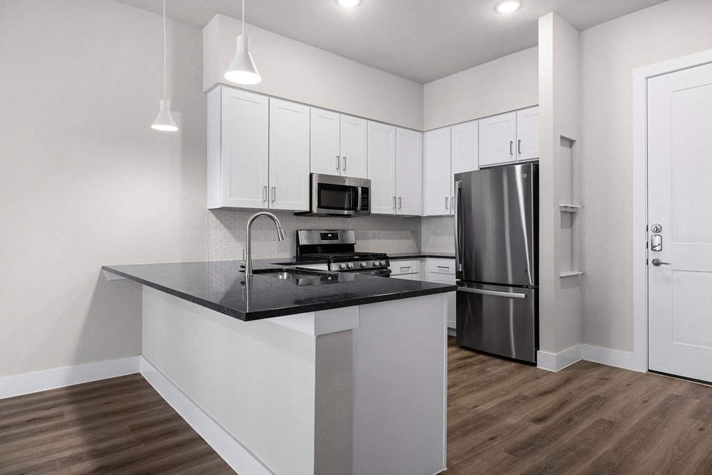 a kitchen with white cabinets and a black counter top