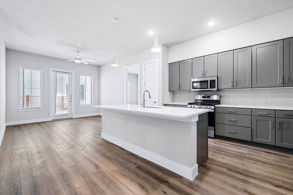an open kitchen and living room with a large white counter top