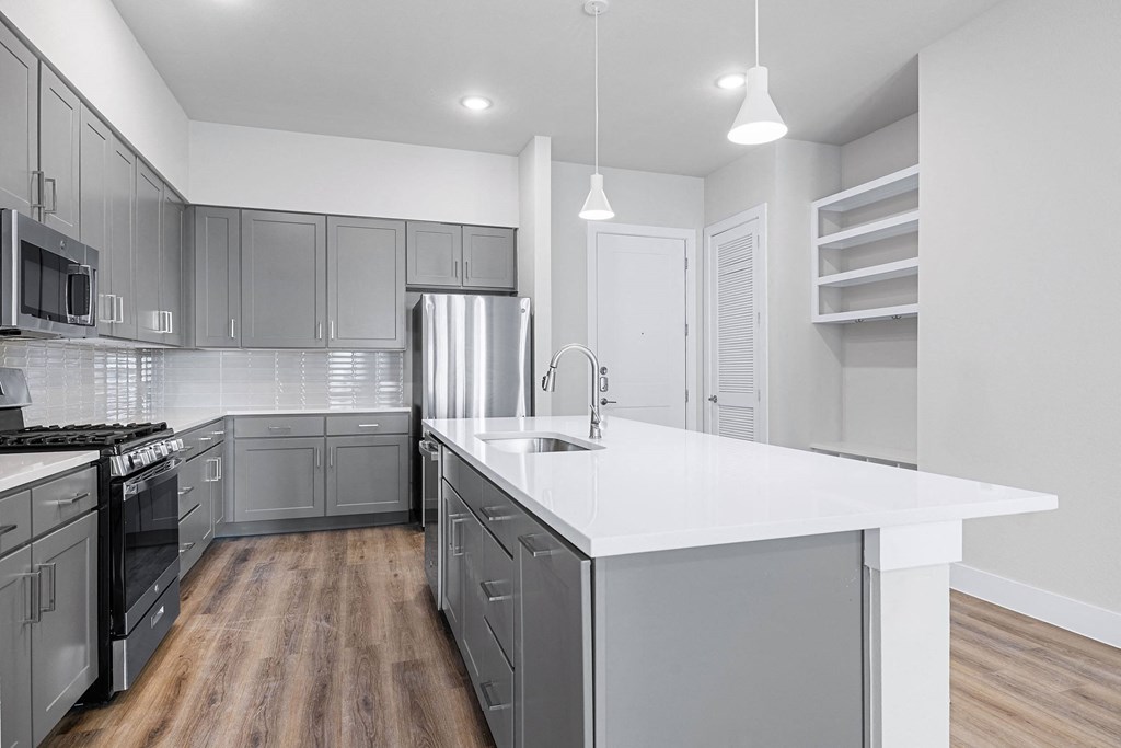 a kitchen with gray cabinets and a white counter top