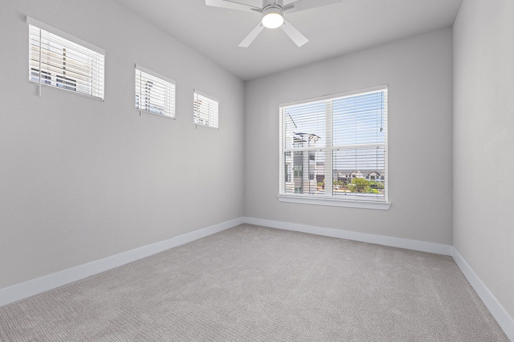 an empty bedroom with a large window and a ceiling fan