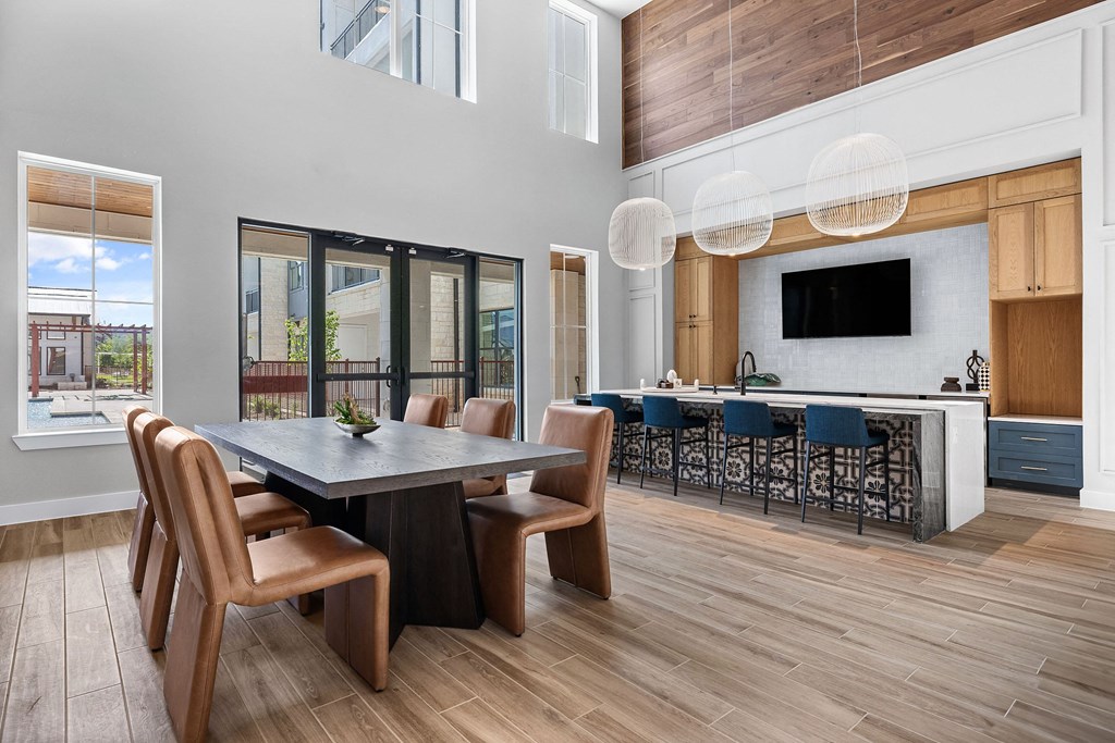 a dining area with a table and chairs and a kitchen with a bar and television