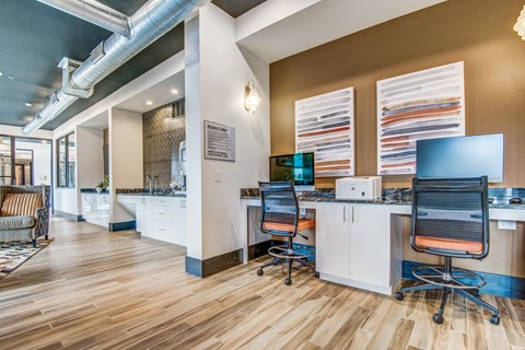 A modern office space with wood flooring and a long table with chairs.