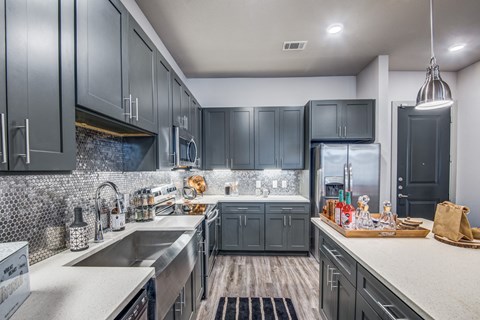 A modern kitchen with dark grey cabinets and a white countertop.