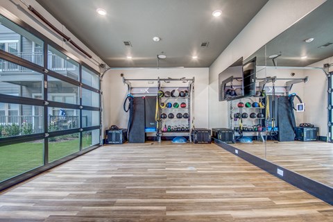 A gym with wooden floors and various exercise equipment.