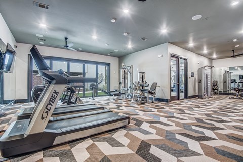 A treadmill with the word "SYBER" on it is in a spacious gym with a tiled floor.