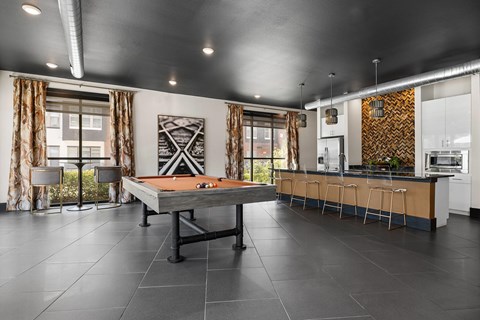 A modern kitchen with a pool table in the middle.