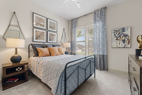 A bedroom with a large bed, a nightstand with a lamp, and a painting on the wall.