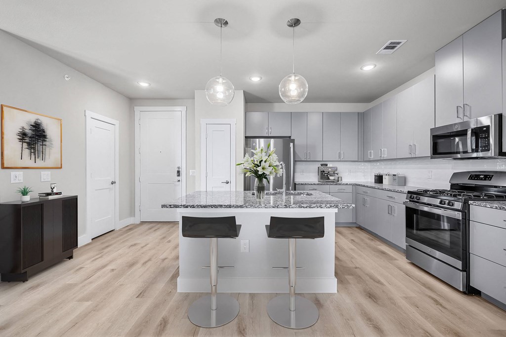 a white kitchen with an island and stainless steel appliances