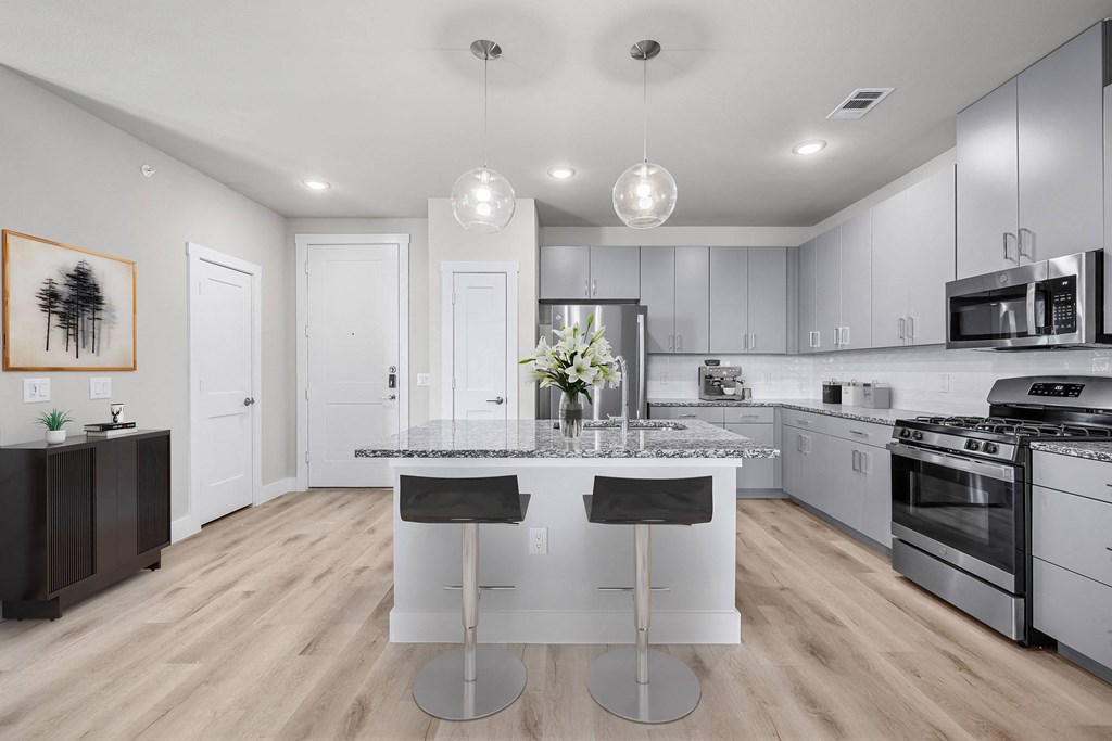 a white kitchen with an island and stainless steel appliances