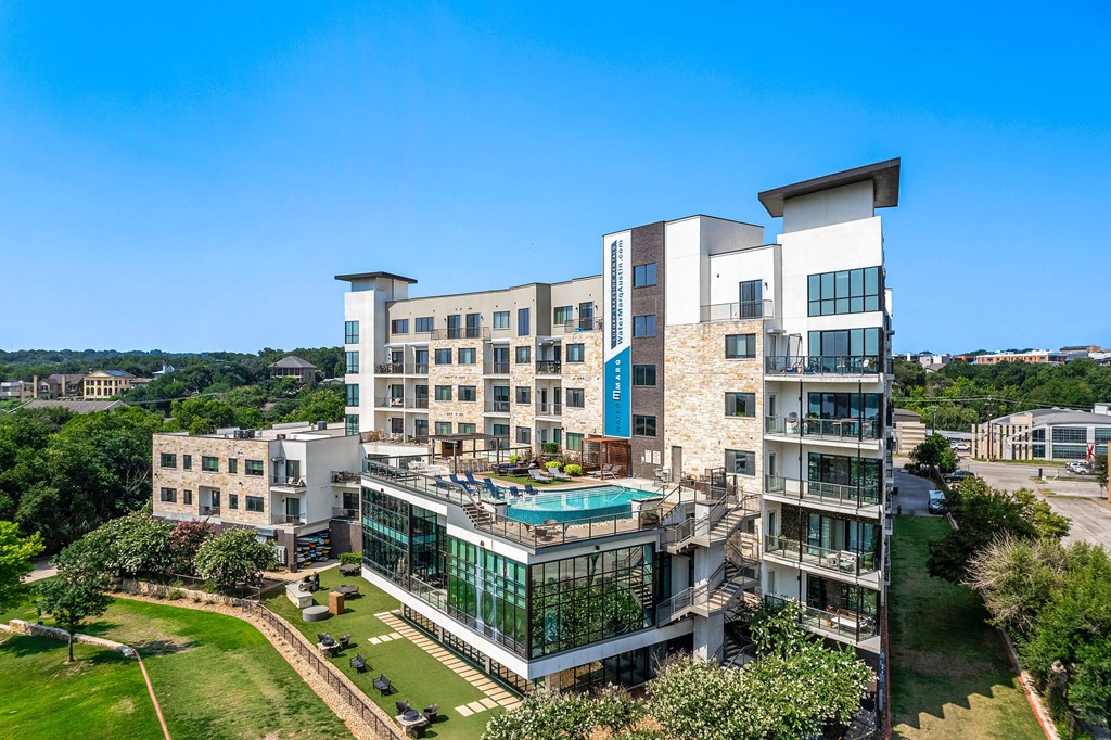 a large building with a pool and trees in front of it