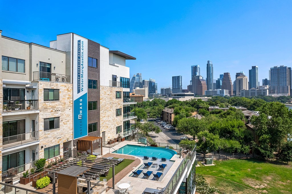 an outdoor pool with a city skyline in the background